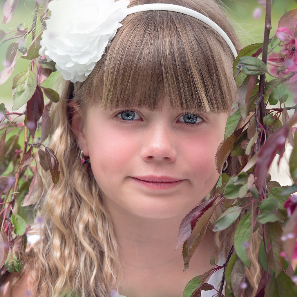 Красивая голубоглазая девочка с белым цветком на голове 