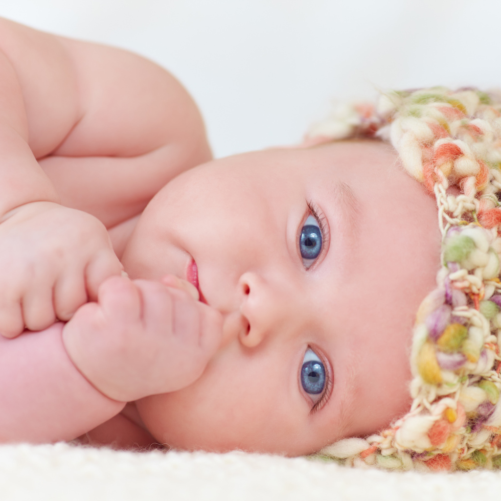 Голубоглазый грудной ребенок в шапке 