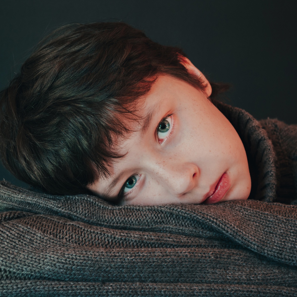 Мальчик в теплом свитере на сером фоне 