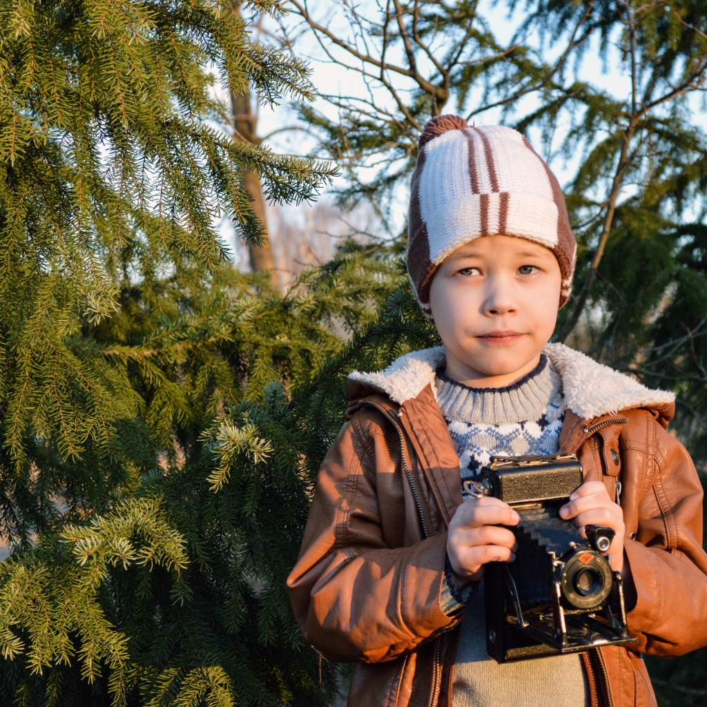 Мальчик с фотоаппаратом у ели
