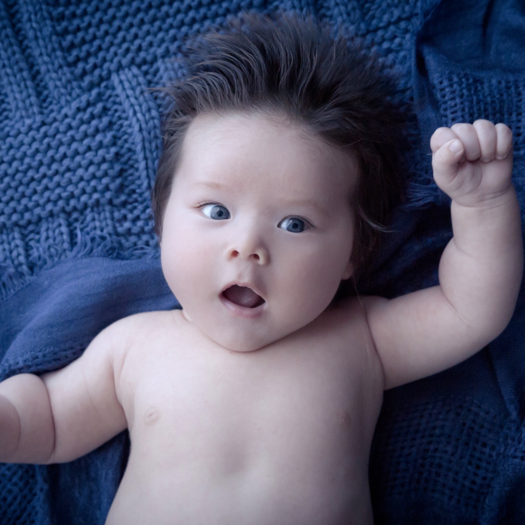 Мальчик с густыми волосами на синем покрывале 