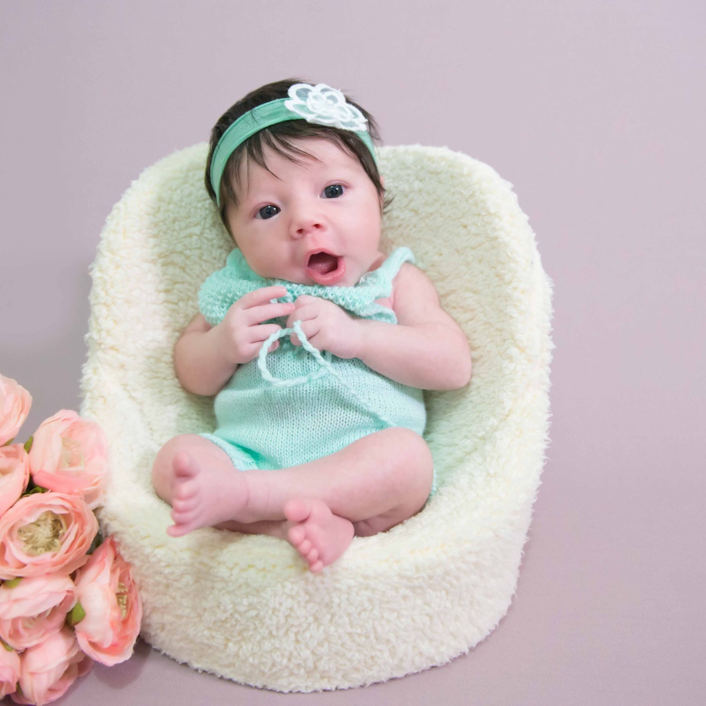 Милая малышка в кресле с букетом цветов