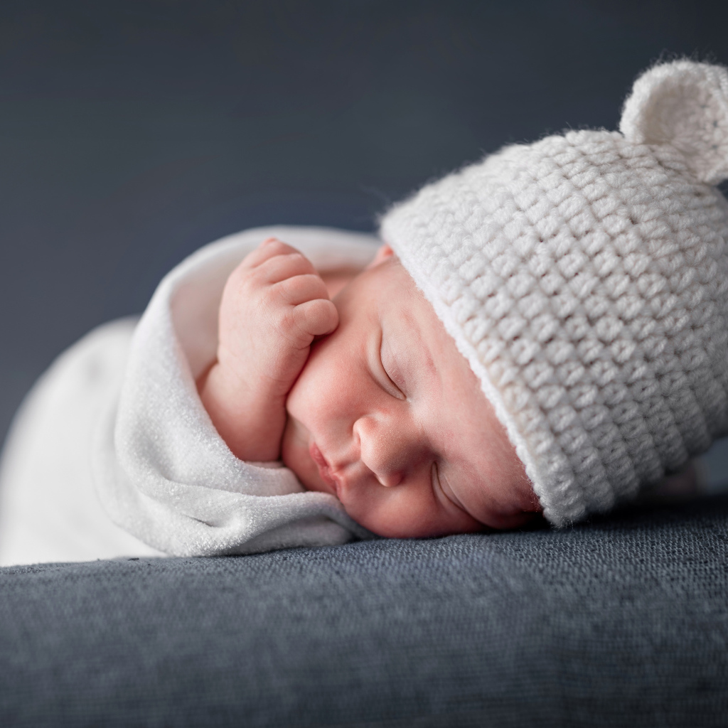 Милый спящий ребенок в белой шапке с ушками