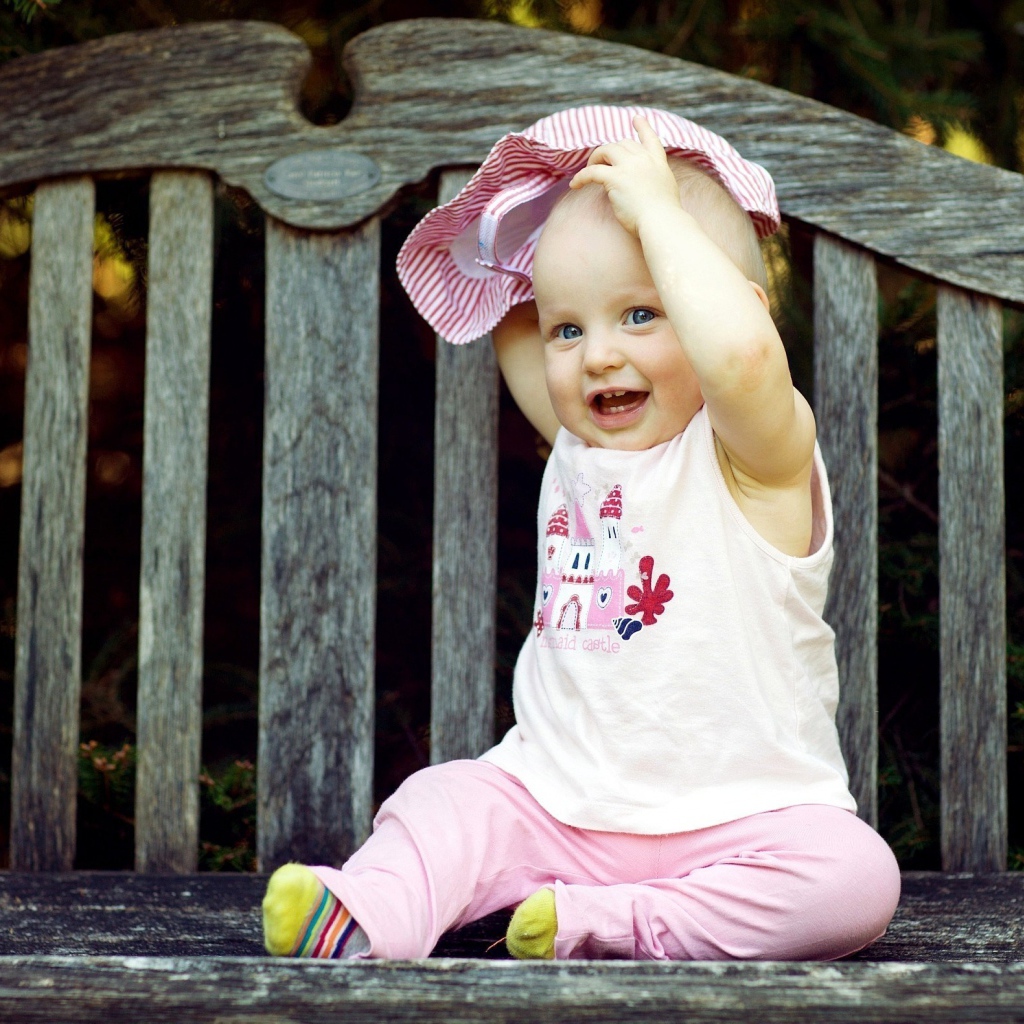 Смешной маленький ребенок сидит на лавке