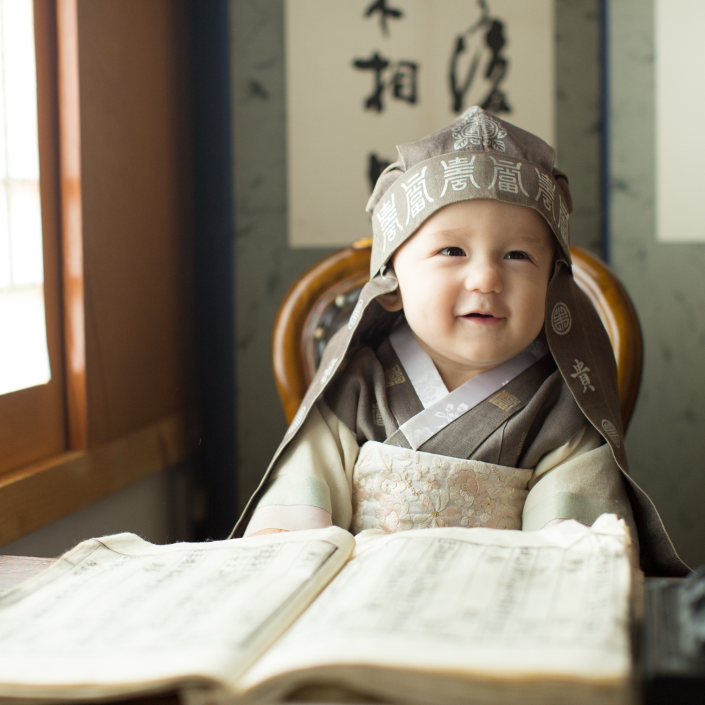 Маленький азиатский мальчик за столом с книгой