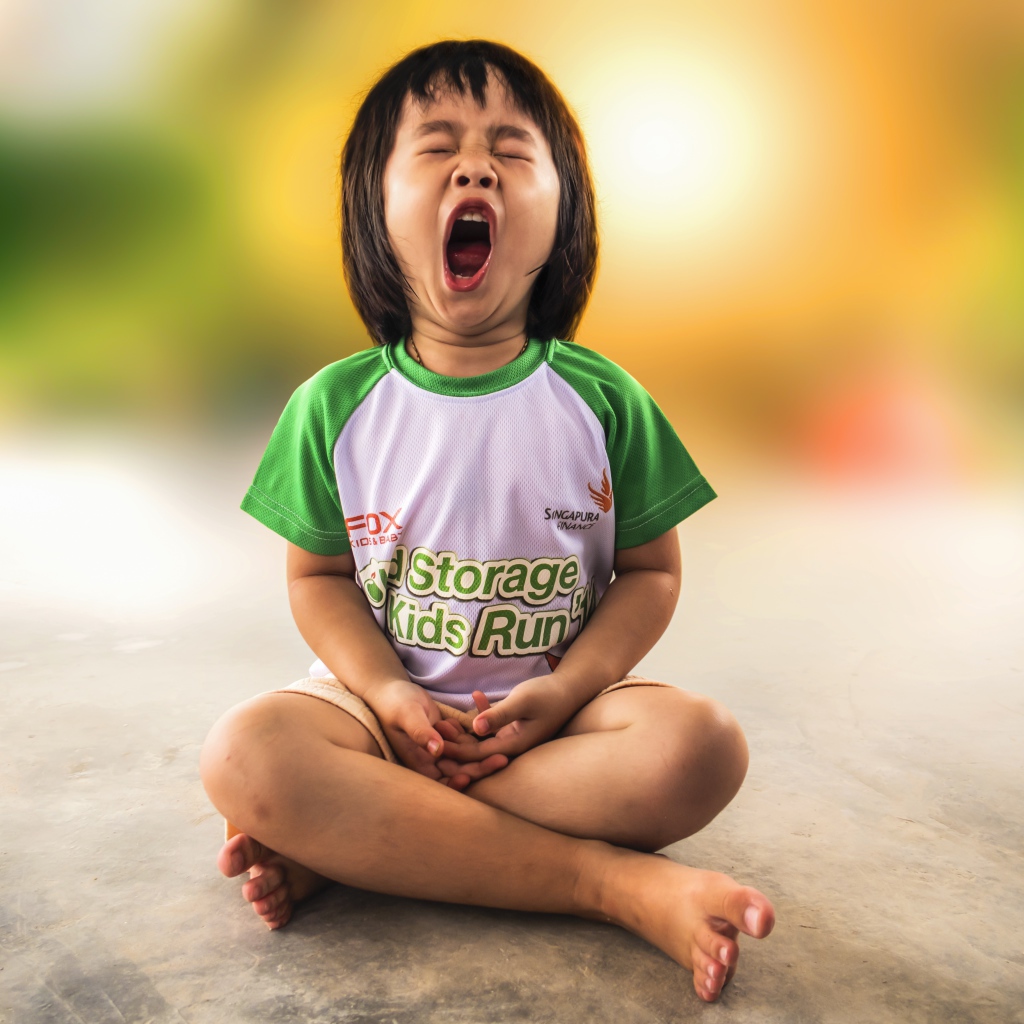 Маленькая девочка азиатка зевает на полу