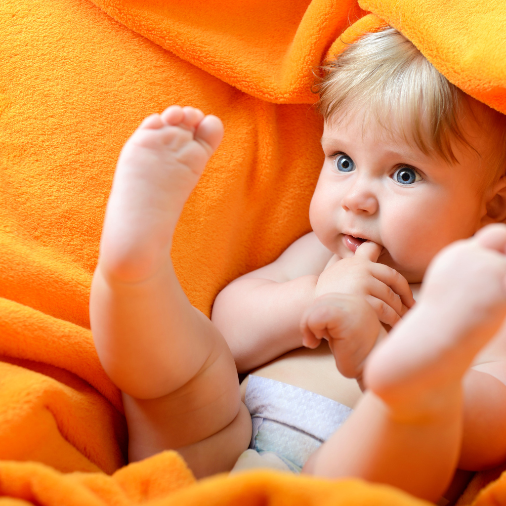 Маленький голубоглазый ребенок в желтом покрывале 