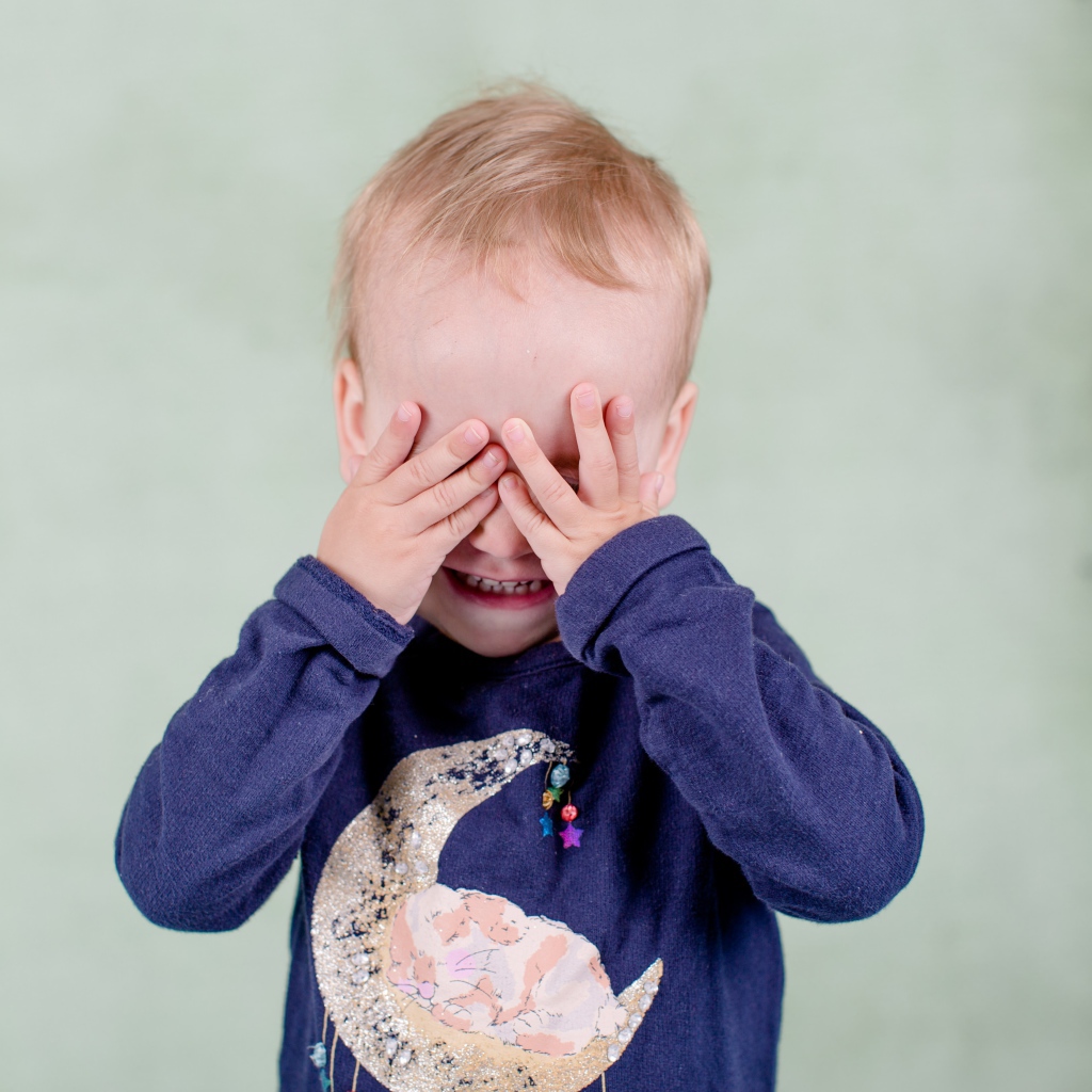 Маленький мальчик закрыл руками лицо 