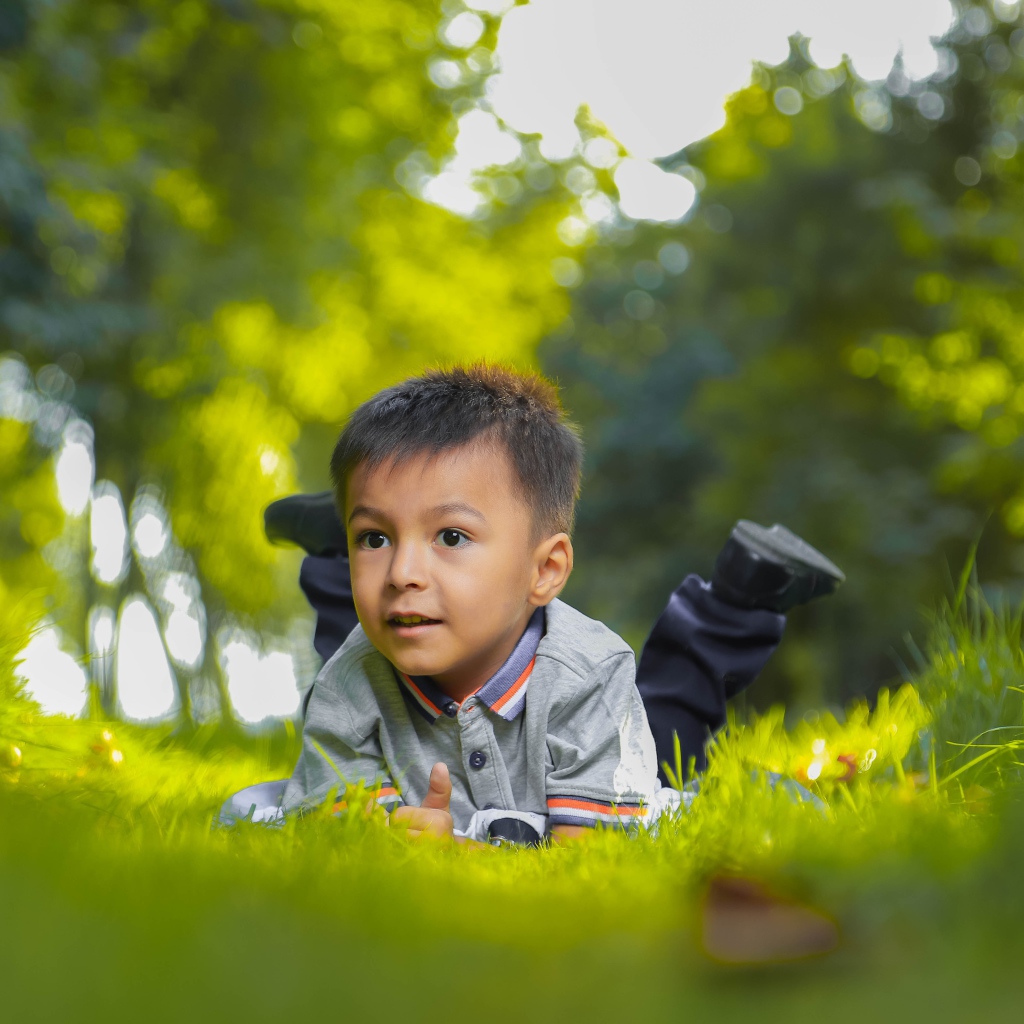 Маленький мальчик лежит на зеленой траве 