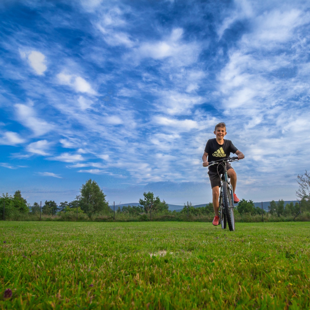 Маленький мальчик катается на велосипеде по полю 
