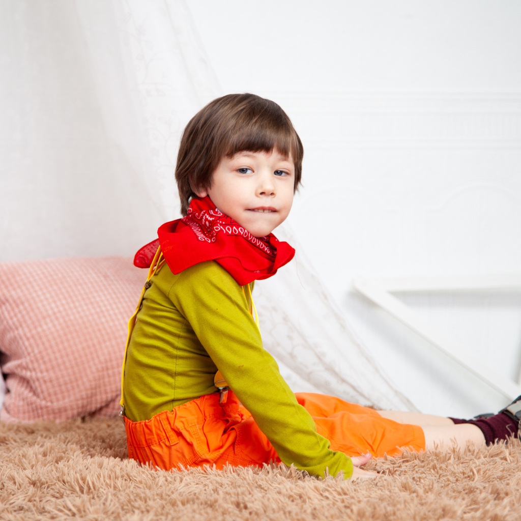 Маленький мальчик сидит на кровати