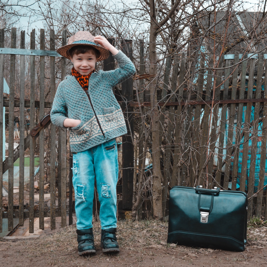 Маленький мальчик с чемоданом у забора