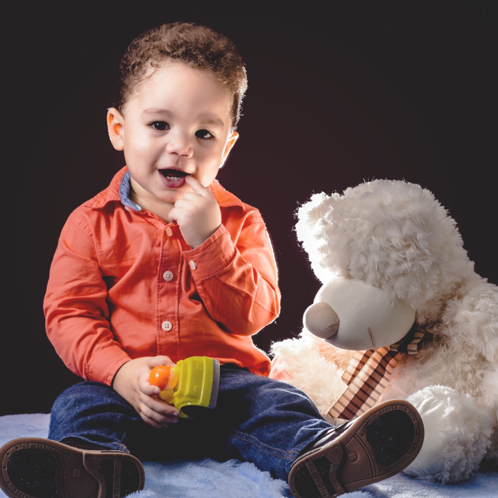 Маленький мальчик с игрушечным медведем на черном фоне