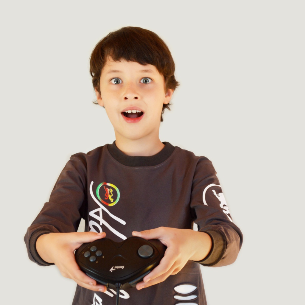 Маленький мальчик с приставкой на сером фоне 