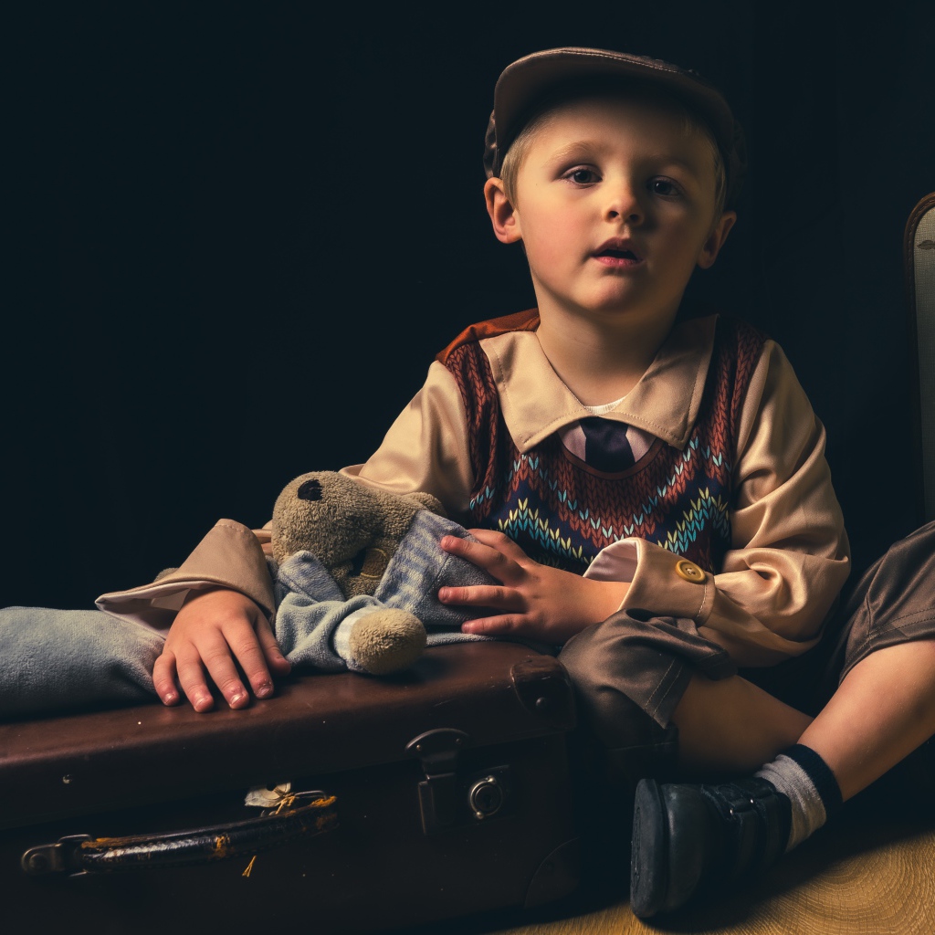 Маленький мальчик с чемоданом и игрушкой