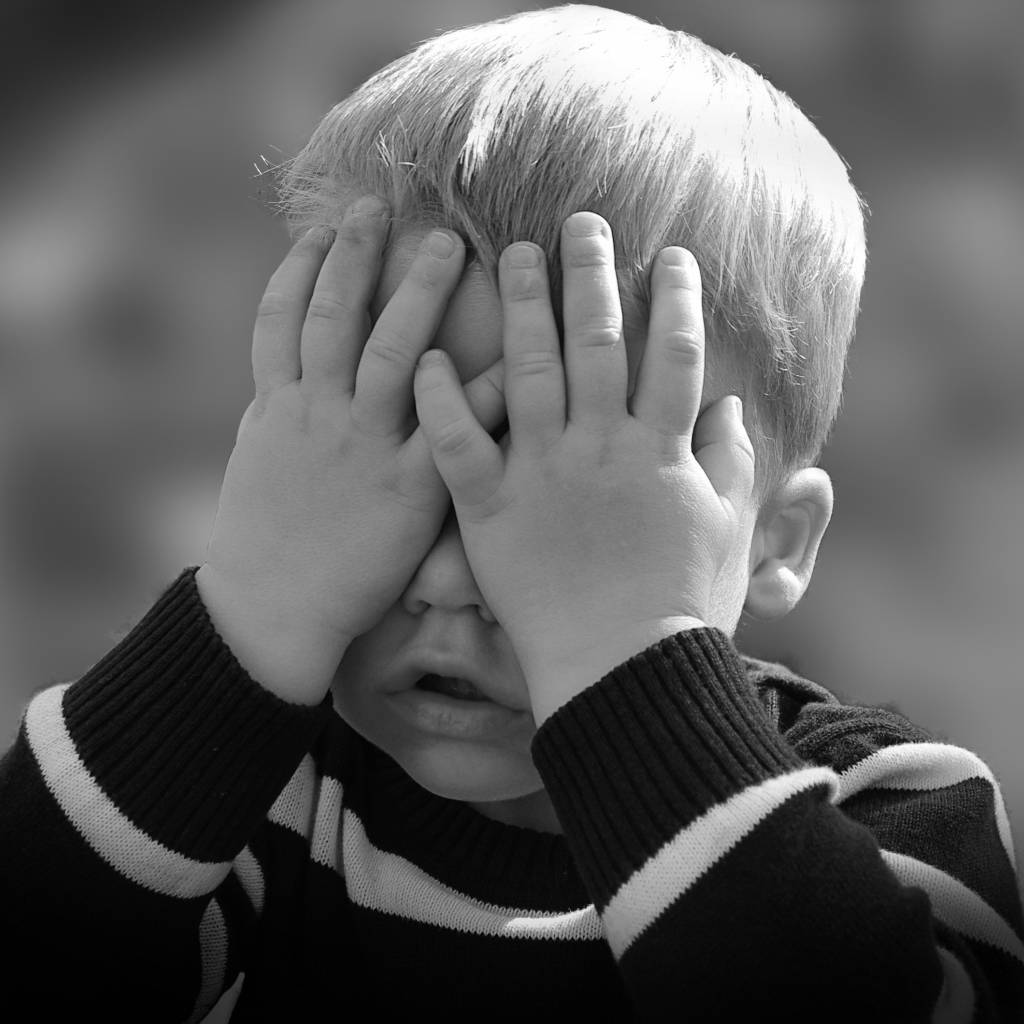 Маленький ребенок закрыл глаза руками