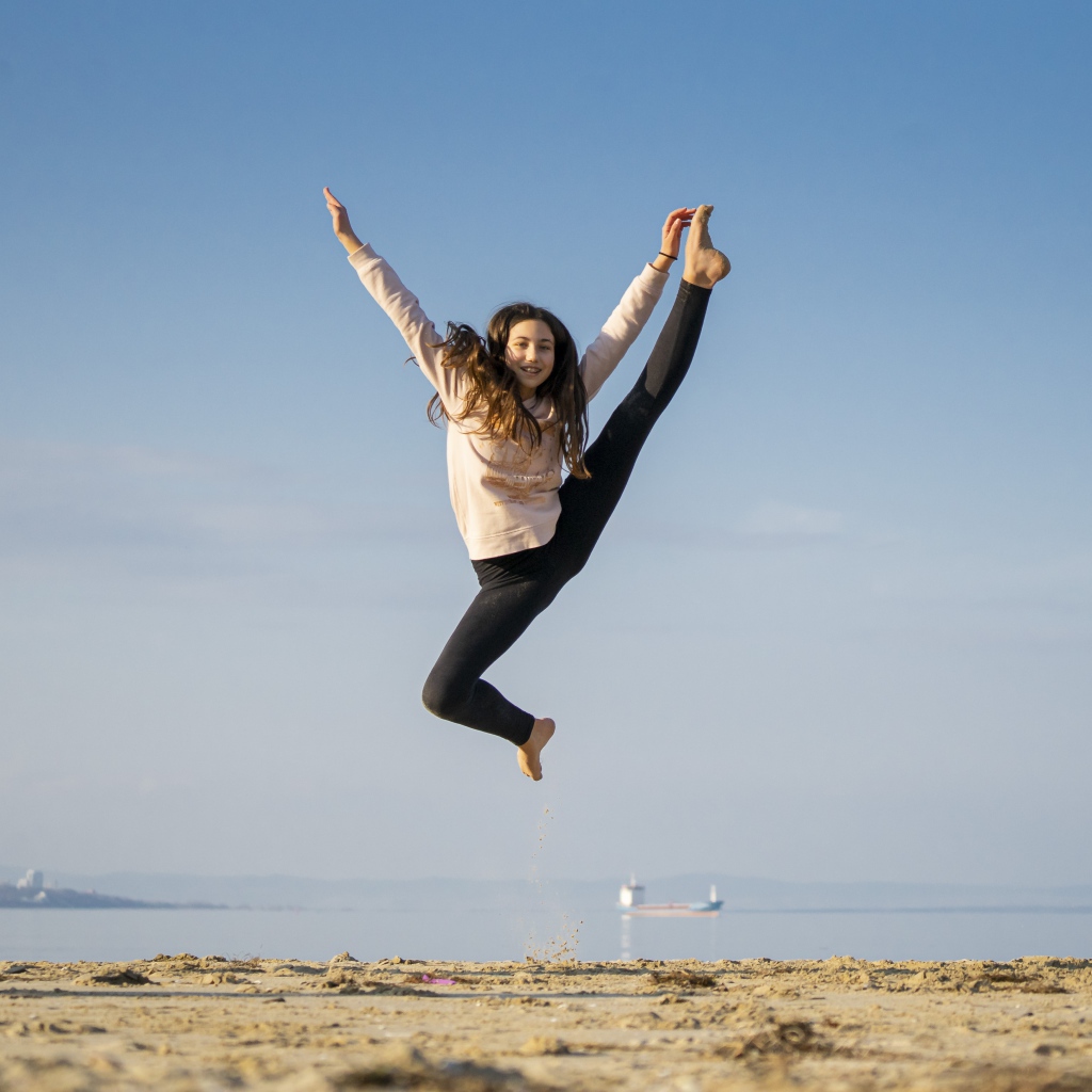 Маленькая девочка гимнастка на песке