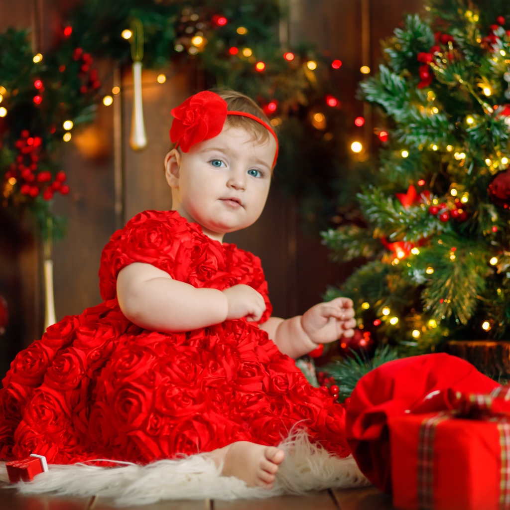 Маленькая девочка в красивом платье у наряженной ели 