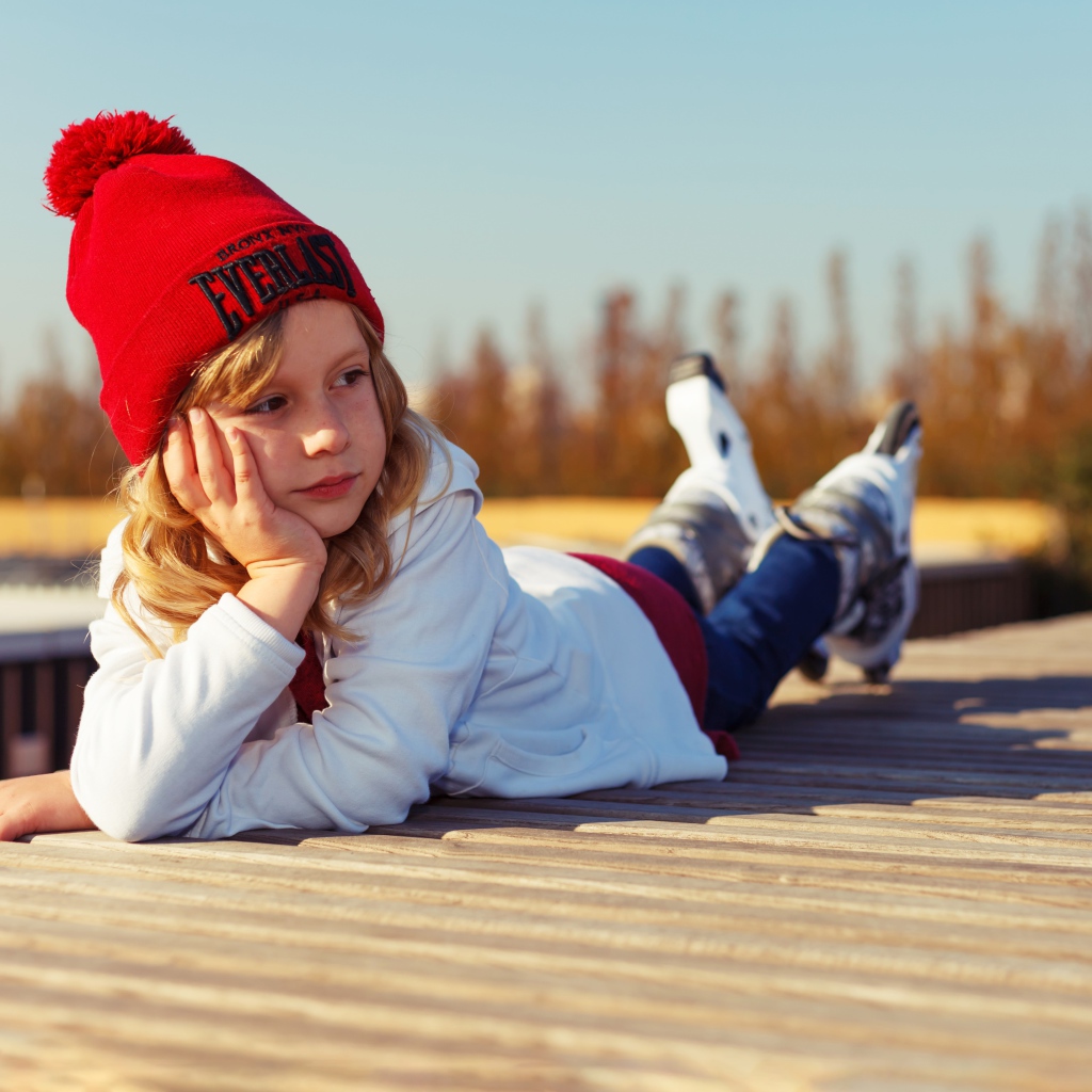 Маленькая девочка лежит на деревянном полу 