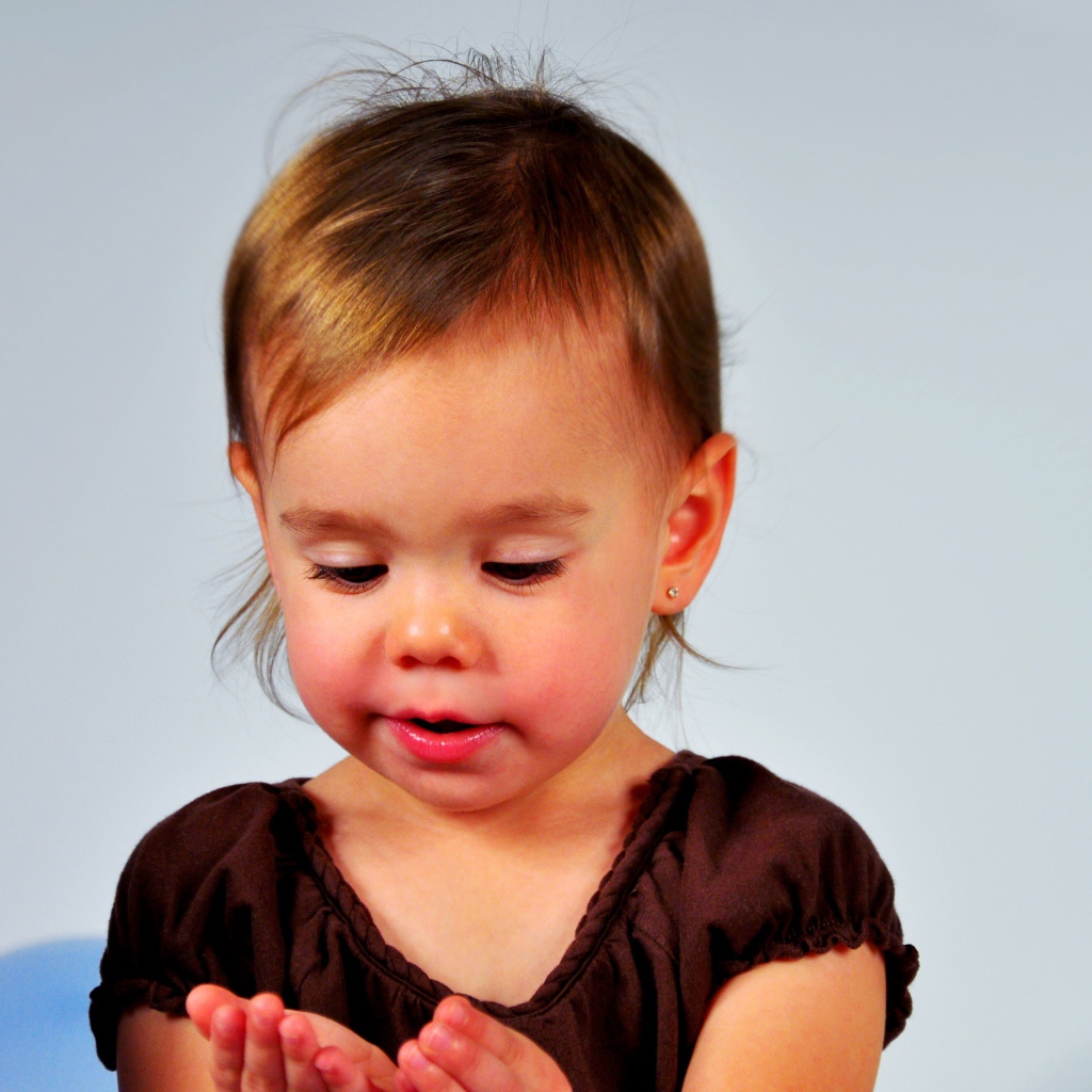 Маленькая девочка смотрит на руки на сером 