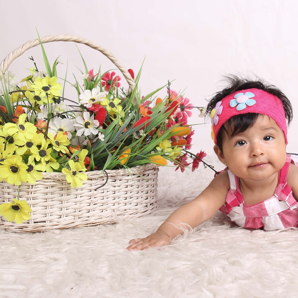 Маленькая девочка рядом с корзиной цветов 