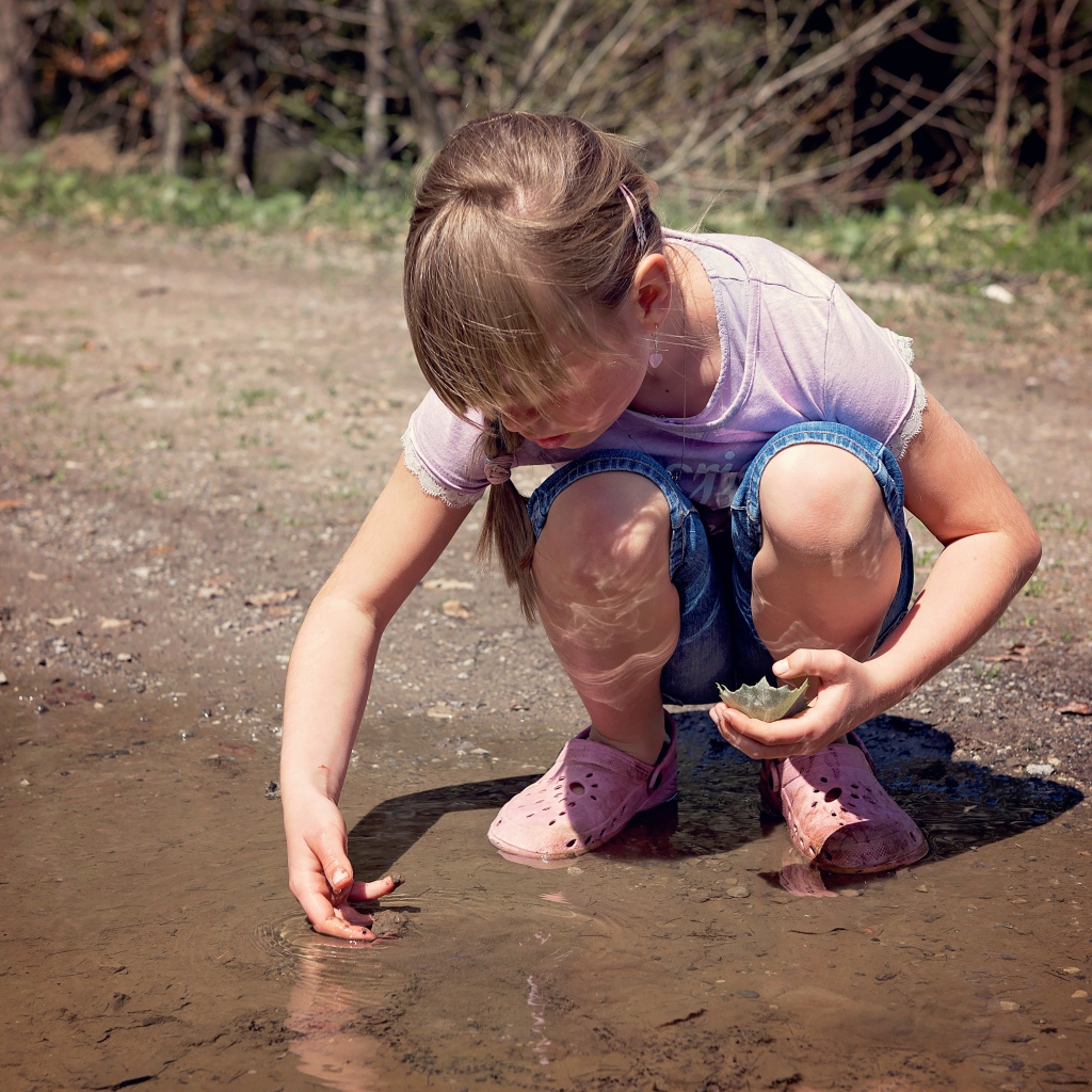 Маленькая девочка играет в луже 