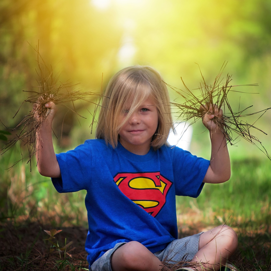 Маленькая девочка сидит на земле с травой