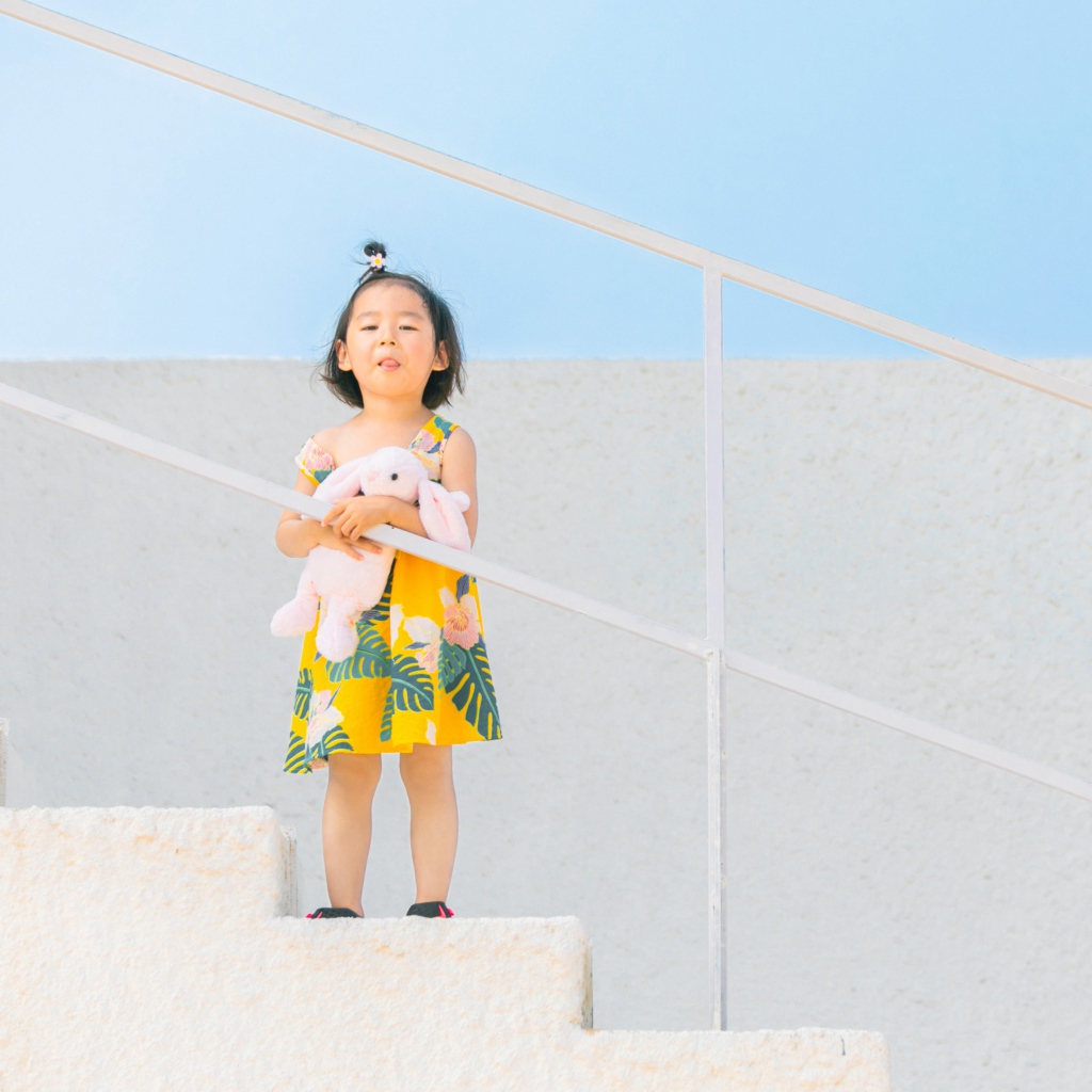 Маленькая девочка с игрушкой на ступеньках 