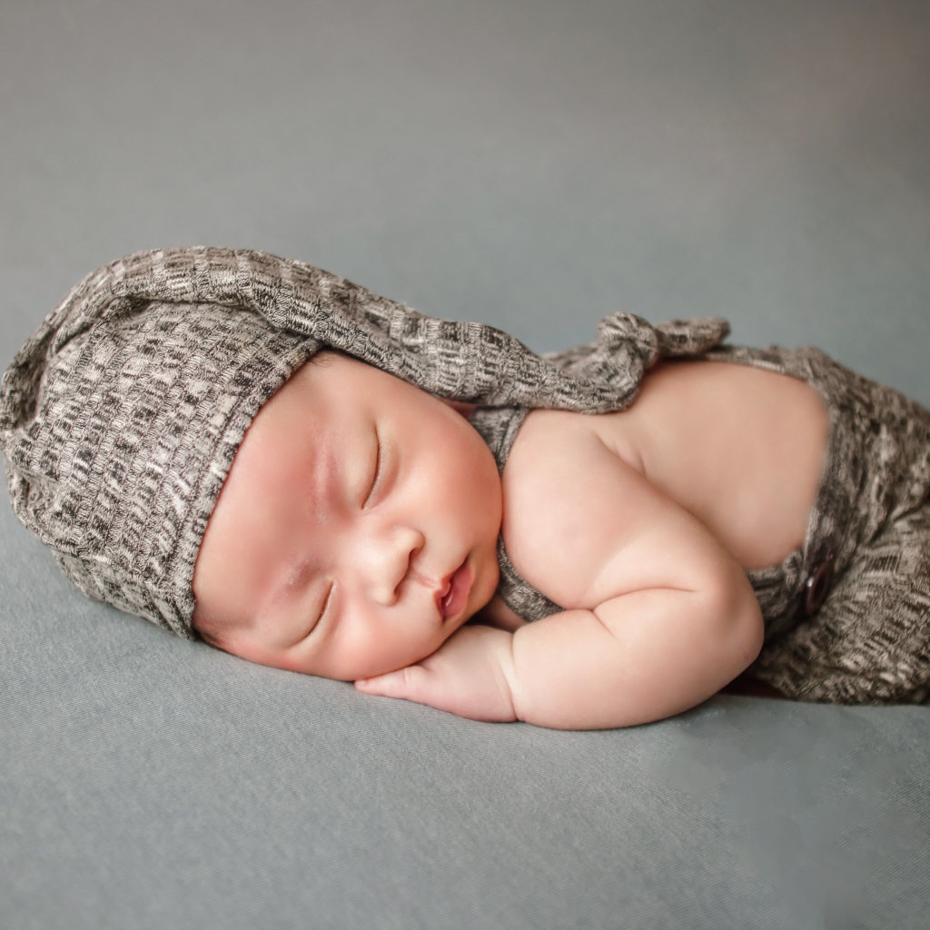 Маленький новорожденный ребенок на сером фоне
