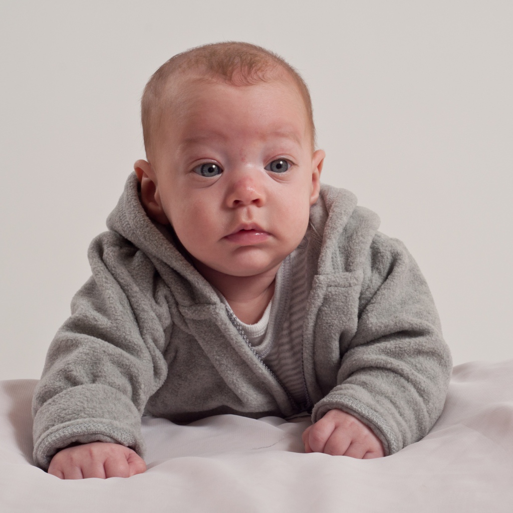 Маленький новорожденный мальчик в сером костюме
