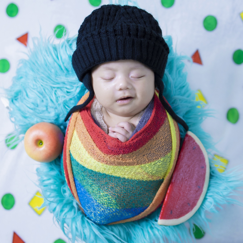 Маленький спящий ребенок в черной шапке 