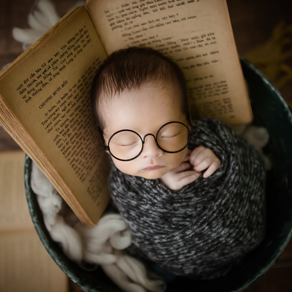 Маленький спящий ребенок в ведре с книгой 