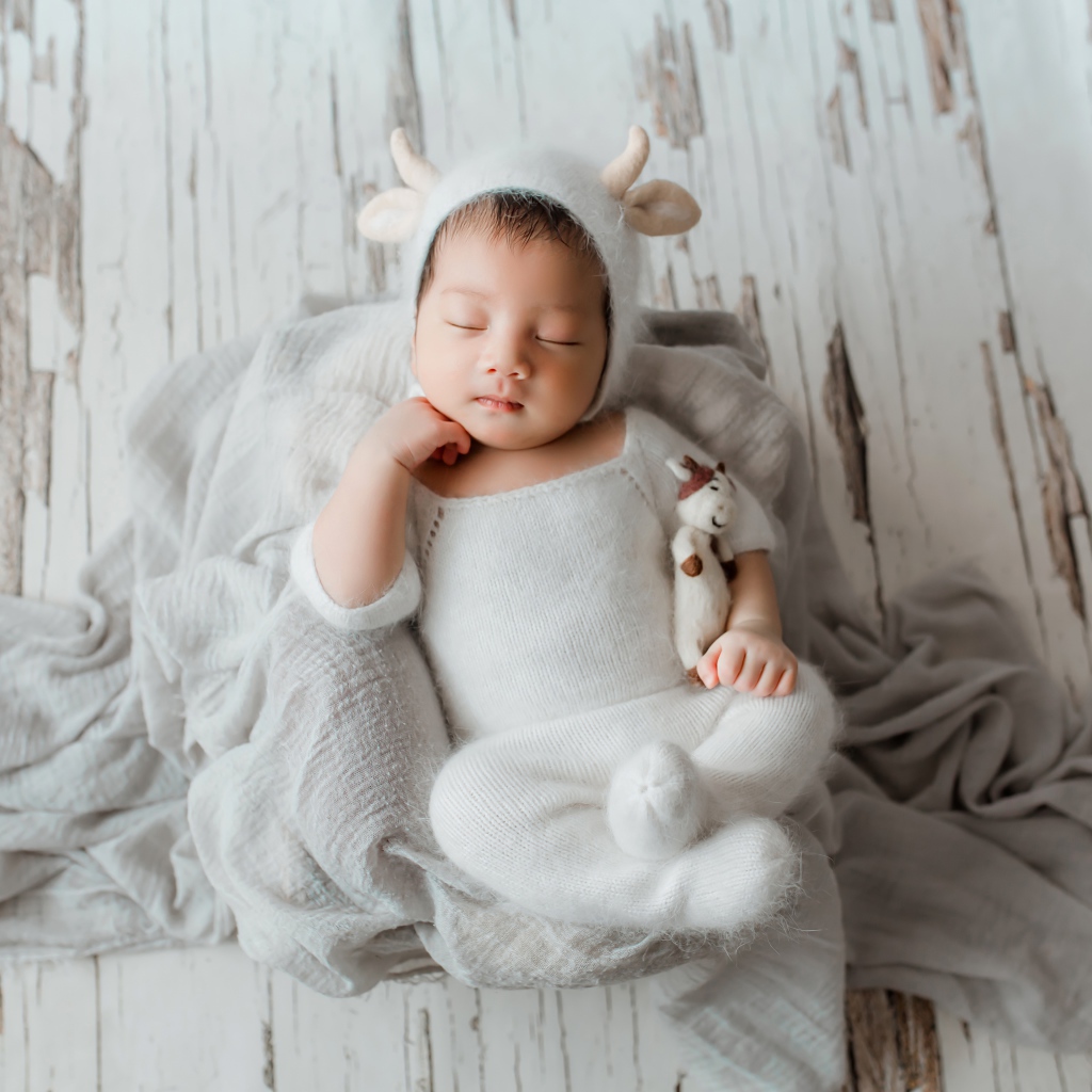 Маленький спящий грудной ребенок в белом костюме