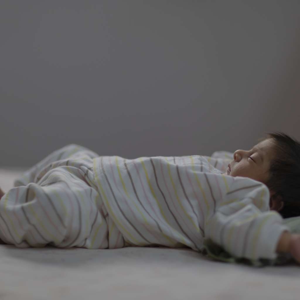 Маленький спящий грудной ребенок на кровати 