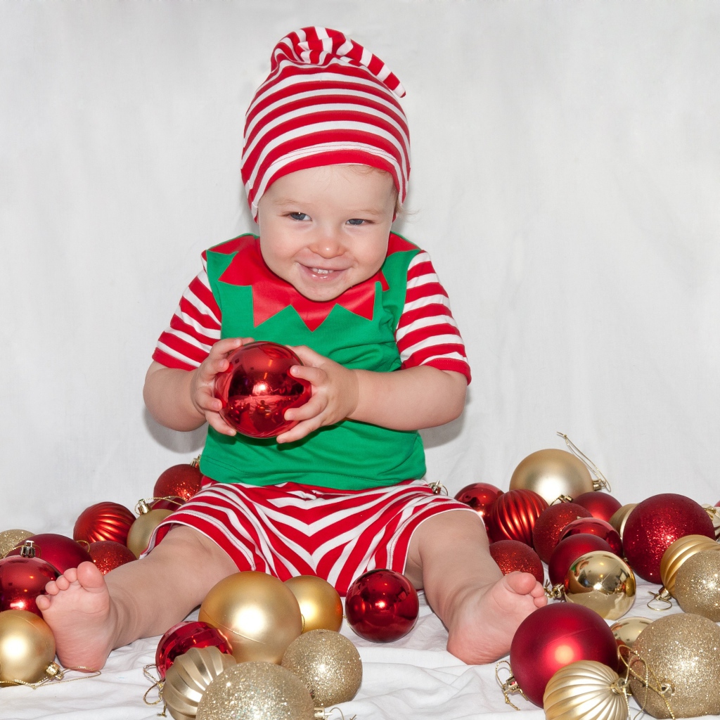 Маленький улыбающийся мальчик с елочными украшениями