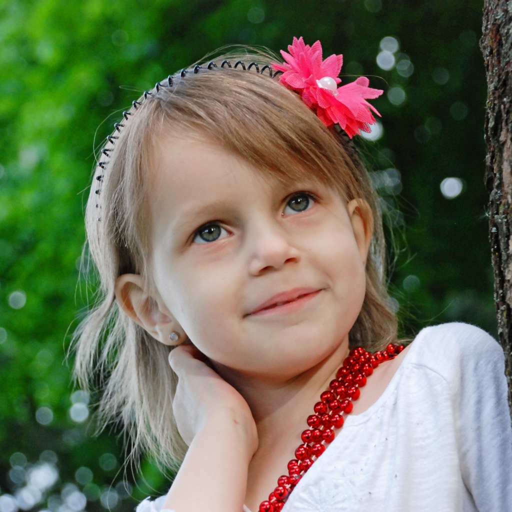 Маленькая улыбающаяся девочка у дерева 
