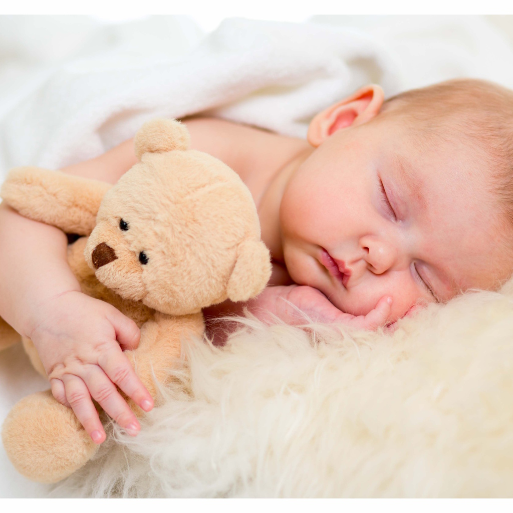 Новорожденный ребенок спит с игрушечным медведем