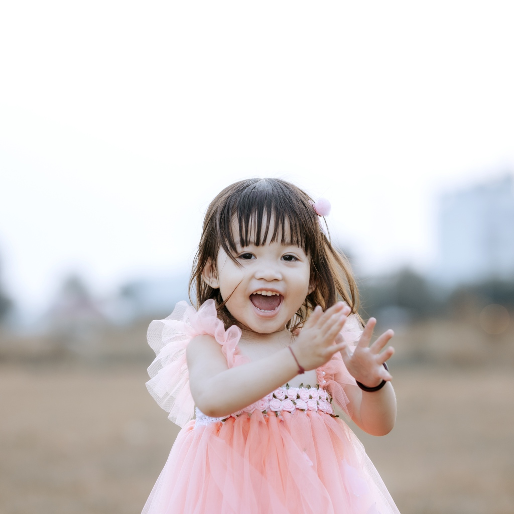 Довольная маленькая девочка в розовом платье 