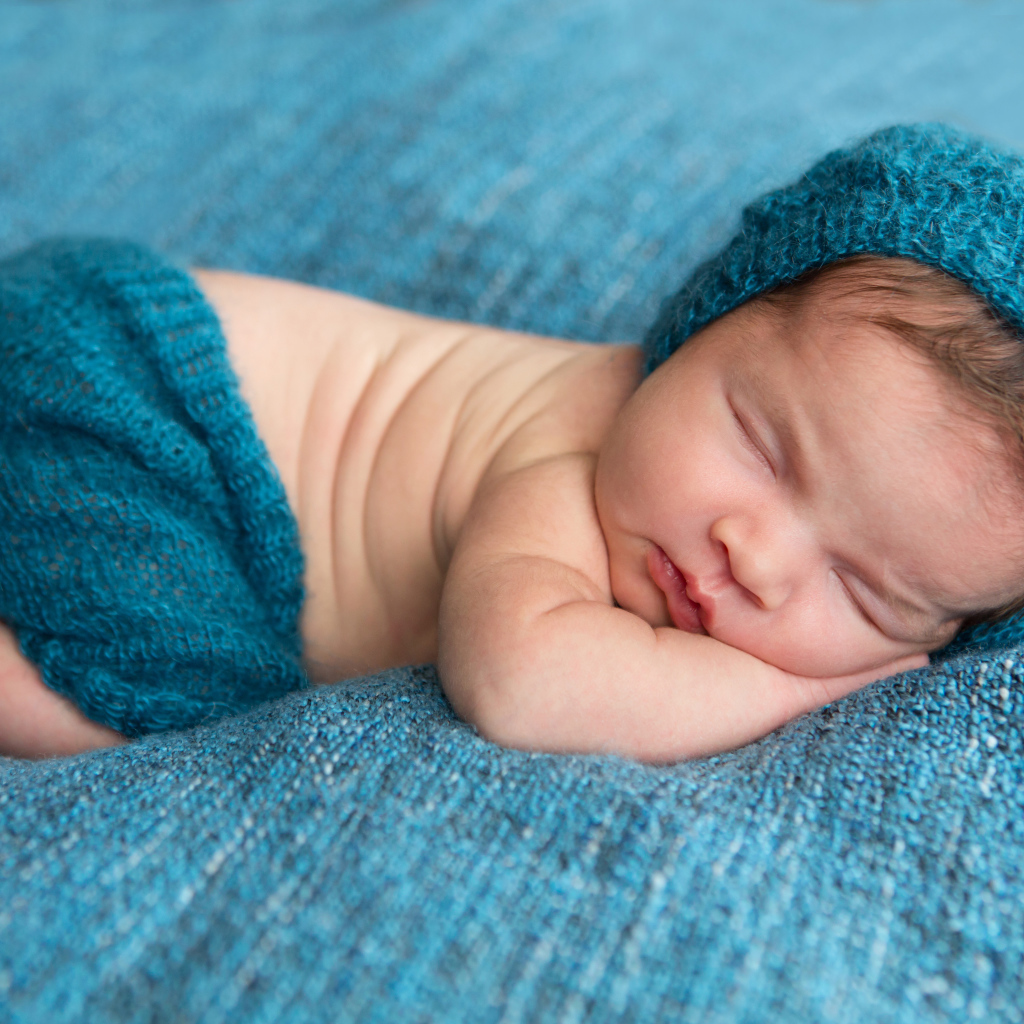 Спящий грудной ребенок лежит на голубом покрывале 