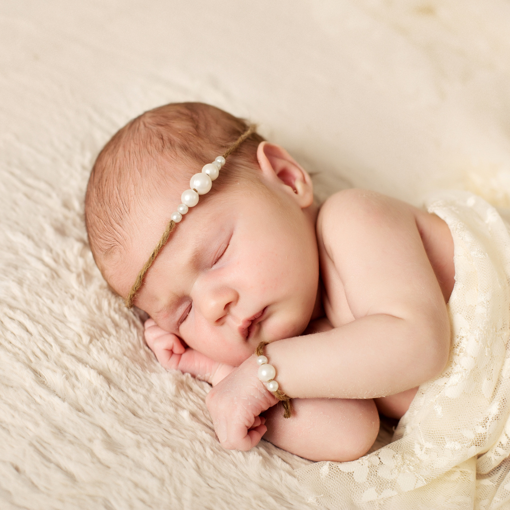Спящий грудной ребенок с украшением с жемчугом на голове 