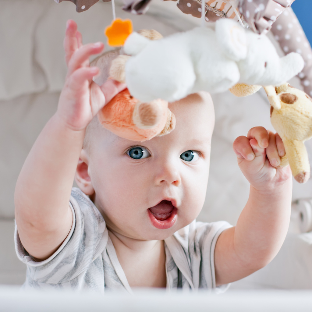 Маленький грудной ребенок в коляске с игрушками 