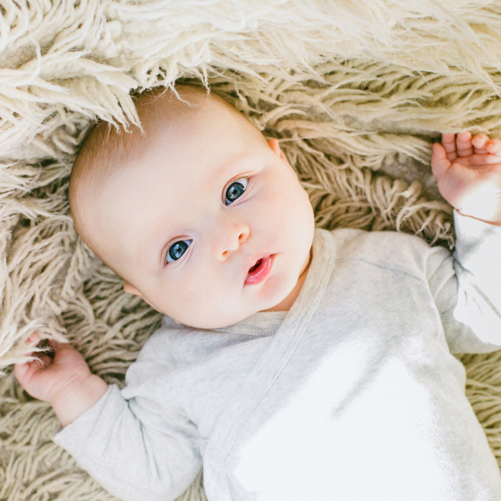 Маленький грудной ребенок на меховом покрывале 