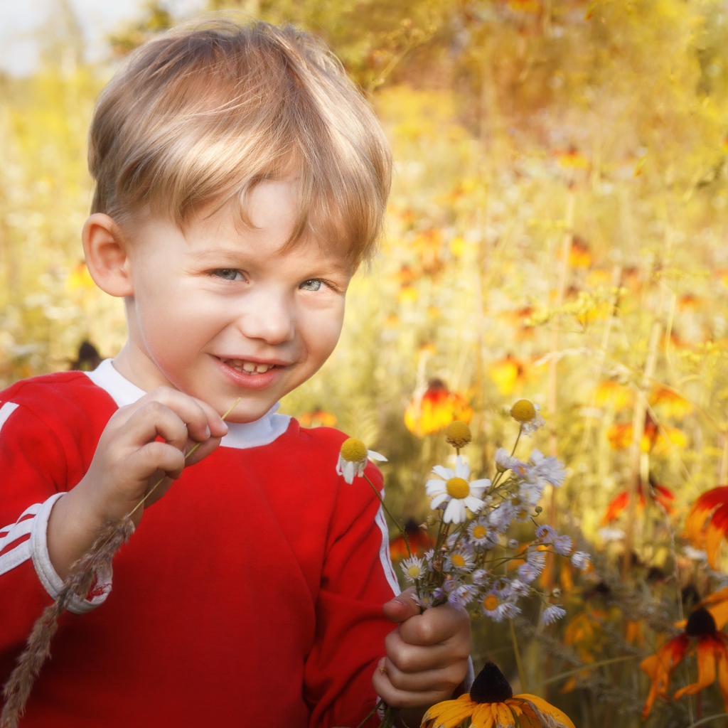 Улыбающийся голубоглазый мальчик с полевыми цветами 
