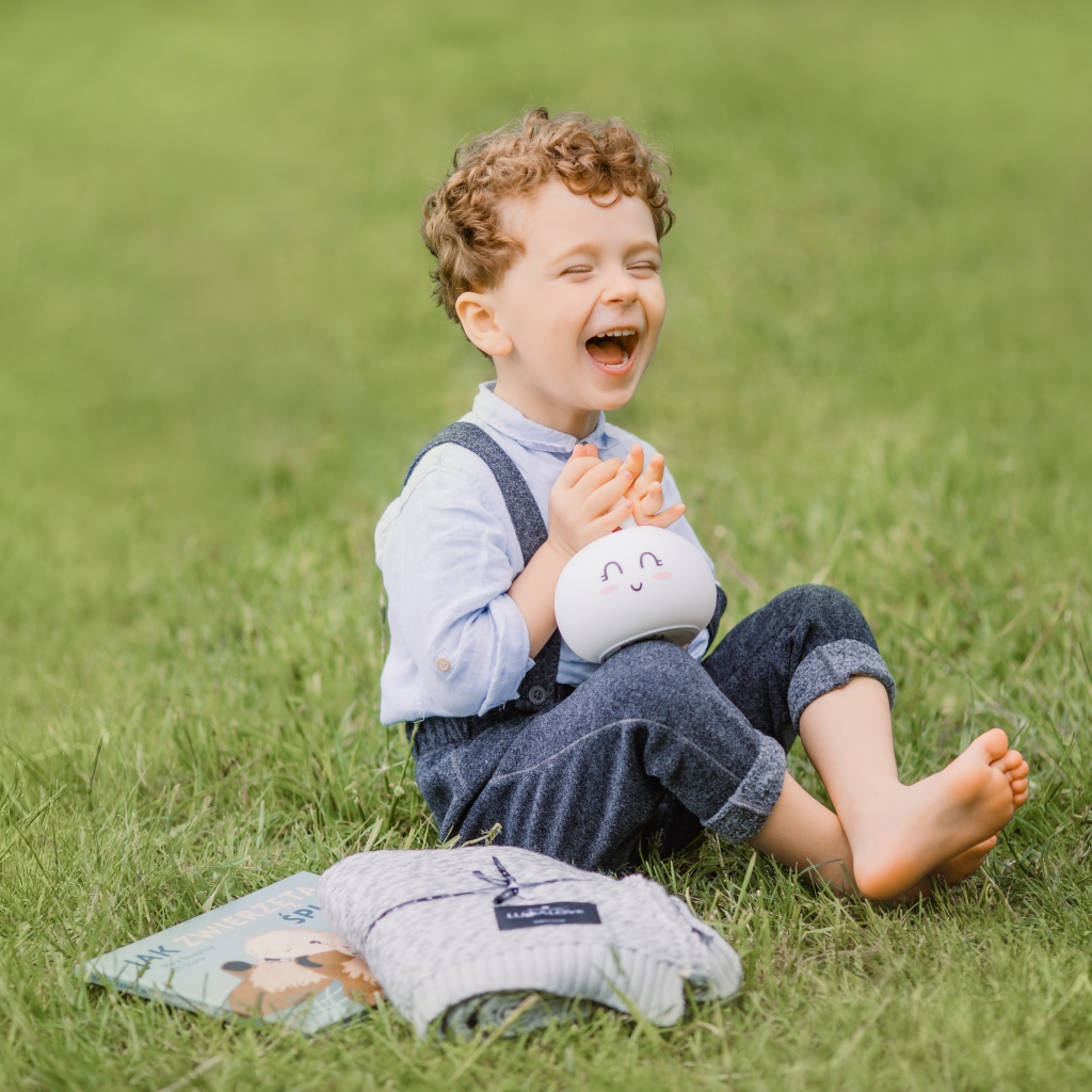Улыбающийся мальчик сидит на траве