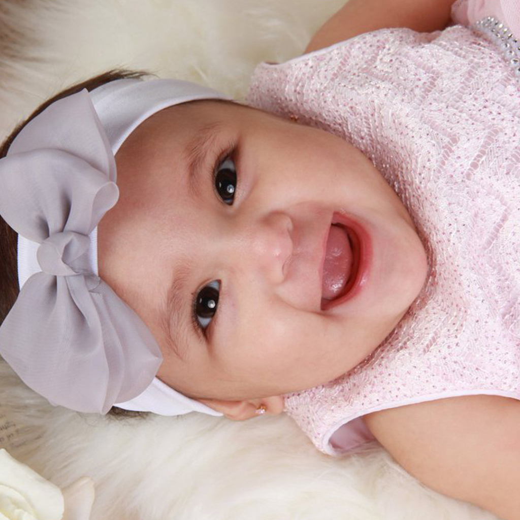 Улыбающаяся девочка в розовом платье с бантом на голове