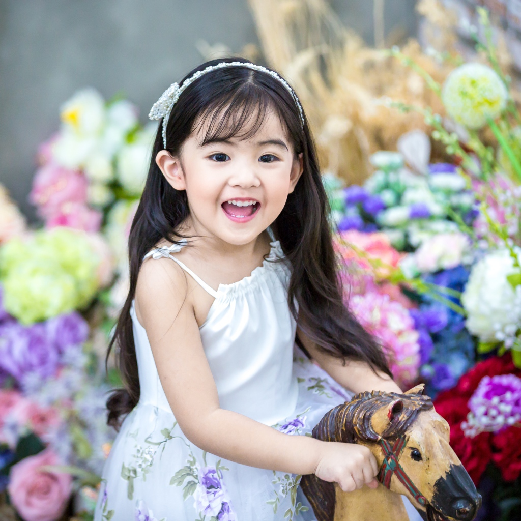 Улыбающаяся маленькая девочка азиатка на лошадке