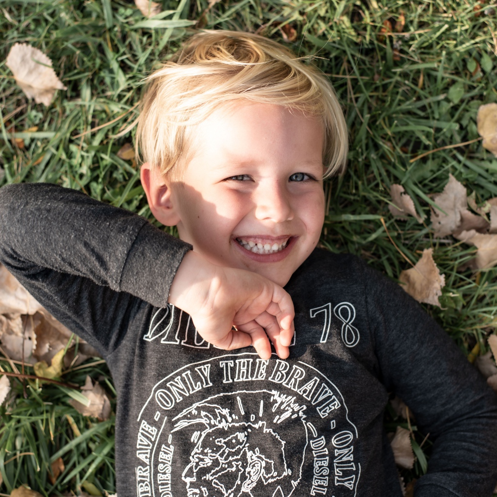 Улыбающийся маленький мальчик лежит на траве