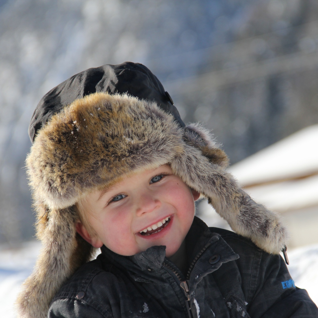 Улыбающийся  маленький мальчик в зимней шапке 