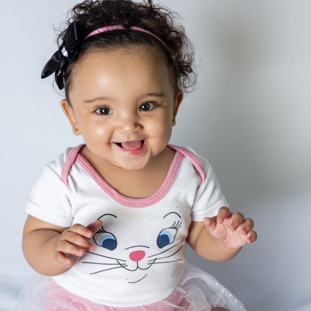 Улыбающаяся маленькая девочка на сером фоне 