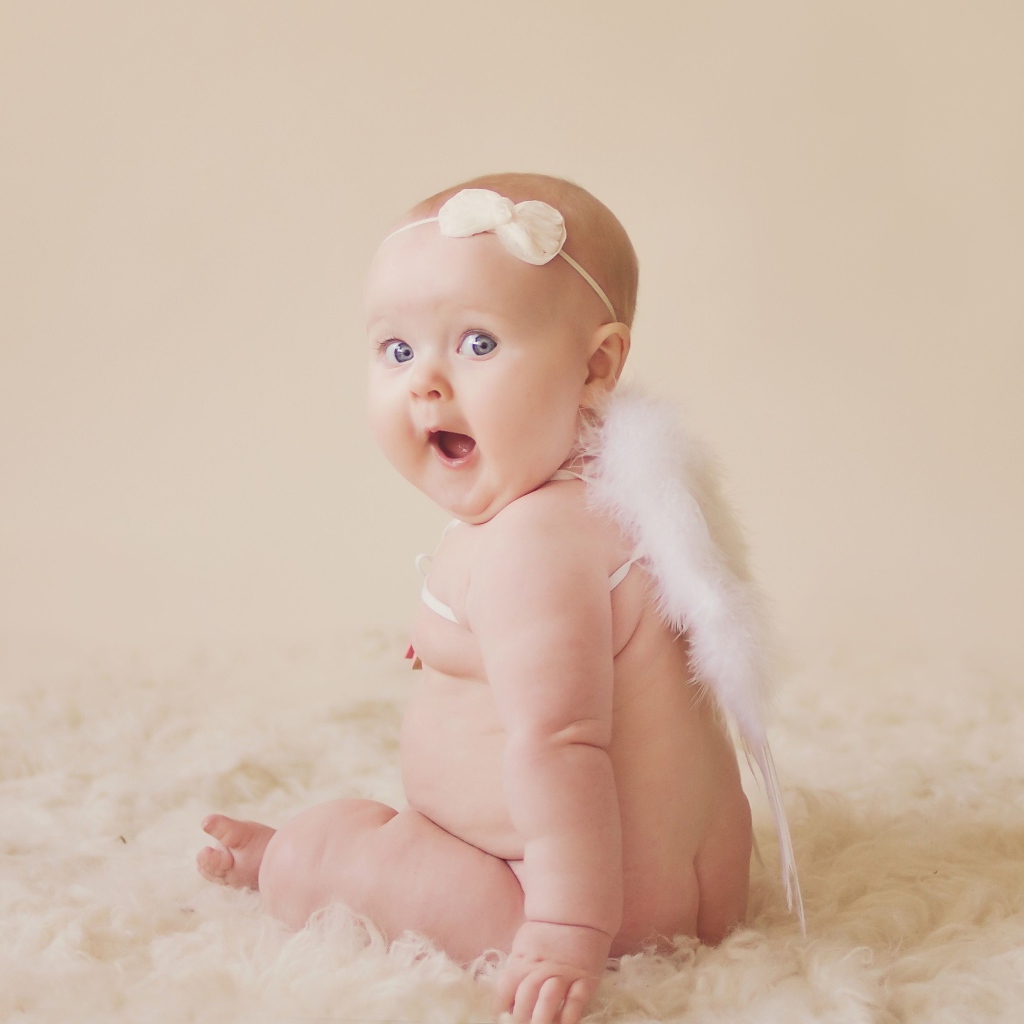 Удивленный грудной ребенок с белыми крыльями за спиной 